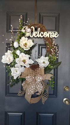 a welcome wreath with white flowers and greenery hangs on the front door for an inviting welcome