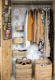 an organized closet with baskets and clothes hanging on the wall, next to two wicker baskets