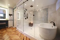 a bathroom with a large tub and wooden flooring on the walls, along with a walk in shower