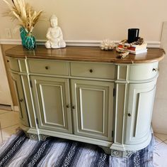 a sideboard with two vases on top of it and a rug in front of it