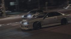 a white car driving down a street at night