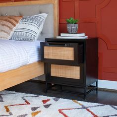 a bedroom with a bed, nightstand and red wall