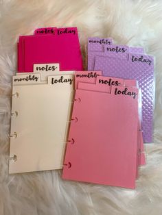 three notebooks with notes written on them sitting on a white furnishing area