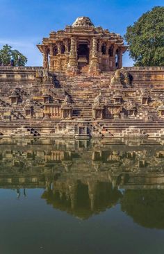 an ancient building with water in the foreground and trees in the backgroud