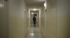 a man walking down a long hallway with white walls