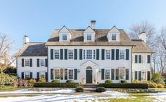 a large white house with green shutters and snow on the ground