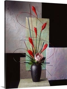 a black vase filled with red flowers on top of a white table next to a painting