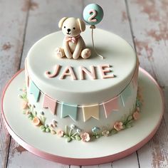 a birthday cake with a teddy bear and number two on the top is decorated in pastel colors