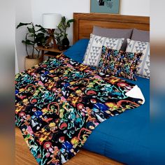 a bed with colorful pillows on top of it in a bedroom next to a plant