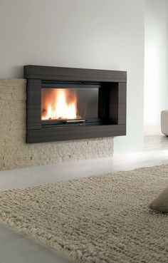 a modern fireplace in a living room with white walls and carpeted flooring is lit by the bright fire