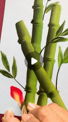 someone is painting bamboo stems with red flowers