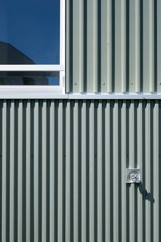 the side of a metal building with a clock on it's face and windows