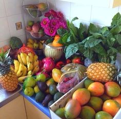 there are many different fruits and vegetables on the counter in this kitchen, including bananas, pineapples, peaches, oranges, avocados