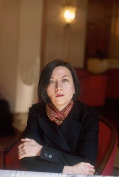 a woman is sitting at a table with her arms crossed and looking off into the distance