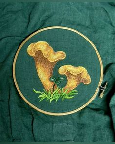 an embroidery project with two yellow mushrooms on green fabric