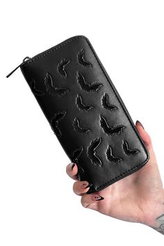 a woman's hand holding a black wallet with birds on the front and bottom