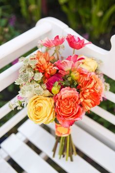 a bouquet of flowers sitting on top of a white bench