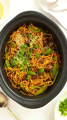 a black bowl filled with noodles and meat