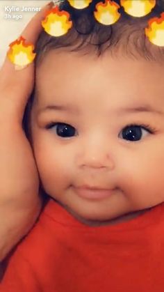 a close up of a person holding a baby with hair clips on their head and smiling at the camera