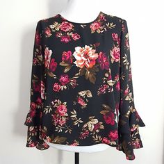 a black top with pink and red flowers is on a white mannequin stand