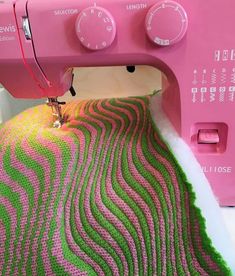 a pink sewing machine sitting on top of a table next to a green and pink blanket