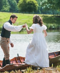 a man and woman in wedding attire standing on a boat by the water holding hands