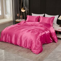 a bed with pink sheets and pillows in a room