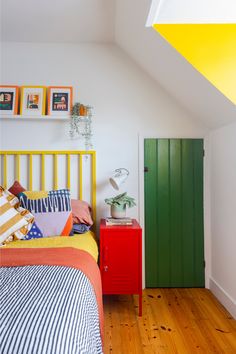 a bed room with a neatly made bed next to a green door and a wooden floor