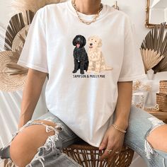 a woman sitting on top of a chair wearing a white shirt with two dogs printed on it