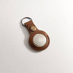 a leather keychain with an apple logo on the front and back, sitting on a white surface