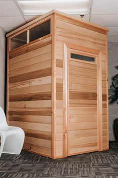 a large wooden sauna in a room with carpeted flooring and potted plants