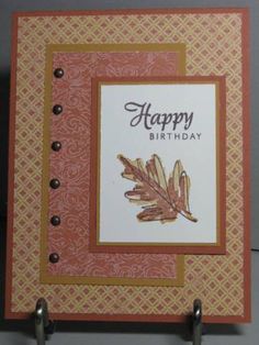 a happy birthday card with an orange and brown leaf design on it, hanging from hooks