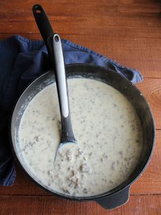 a pan filled with food on top of a wooden table next to a blue napkin