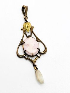 Gold Diggers Black Hills gold Pink cameo freshwater pearl gold filled pendant. This stunning antique piece of Black Hills Gold jewelry was created by Gold Diggers. Black Hills gold has several different designers that work using the specific leaf elements that BHG has been known for creating. This beautiful gold filled pendant has a yellow gold leaf accent above a prong set pink cameo with a freshwater pearl drop. Stamped with the unique W symbol that Gold Diggers uses on the back of the bail. F Antique Oval Pearl Pendant Jewelry, Antique Bronze Necklace With Cabochon, Victorian Brass Cabochon Jewelry, Heirloom Cameo Pendant Jewelry, Oval Cameo Pendant In Brass, Cameo Brass Oval Pendant Jewelry, Oval Cameo Pendant Jewelry In Brass, Brass Cameo Oval Pendant Jewelry, Elegant Antique Gold Cabochon Necklace