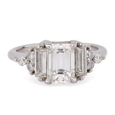 an emerald cut diamond ring with three stone shoulders