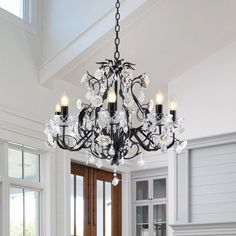 a chandelier hanging from the ceiling in a room with white walls and windows