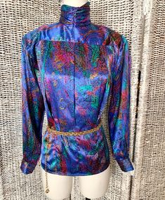 "This vintage top has a fab artistic print in bold jewel tones. Silky polyester with high neck. Tapered fit gives an hourglass illusion. Back button closures. (Please note: no belt included with this listing. For photo purposes only.) Overall wonderful vintage condition! No holes, tears or spots. From a smoke free environment. Convos invited. A great addition to your closet or give as a gift for the vintage lover in your life! FITS SIZE M-L (Size label 6) Please note measurements below. Measurem Fall Formal Multicolor Tops, Fitted Multicolor Top For Formal Occasions, Formal Fitted Multicolor Top, Elegant Fitted Multicolor Blouse, Elegant Multicolor Evening Blouse, Fitted Abstract Print Top For Party, Fitted Blue Top With Vibrant Print, Fitted Printed Purple Blouse, Fitted Purple Printed Blouse