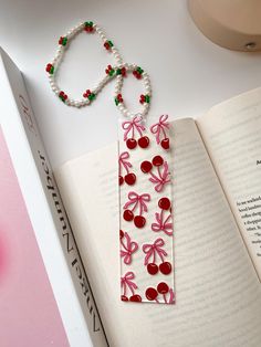 a bookmark with beads and bows on it sitting next to an open book,