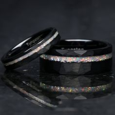 two black wedding bands with multicolored opal inlays