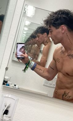 a shirtless man taking a selfie in front of a mirror with his cell phone