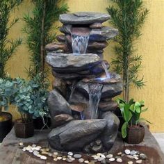 a water fountain surrounded by rocks and plants