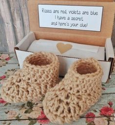 a pair of crocheted slippers sitting in front of a box that says roses are red, violets are blue i have a secret and there's your clue