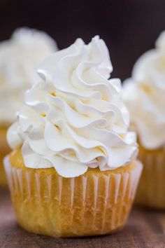 three cupcakes with white frosting sitting on a table