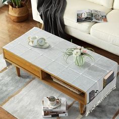 a coffee table with two cups on it in front of a white couch and rug