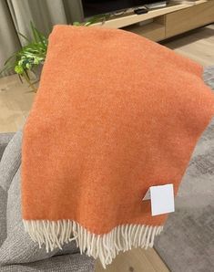 an orange and white throw sitting on top of a gray couch next to a tv