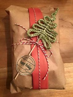 a wrapped present sitting on top of a wooden table next to a red ribbon and twine