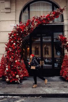 a woman walking past a building decorated with christmas decorations