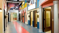 an empty hallway with multiple doors leading to different rooms and lights on either side of the door