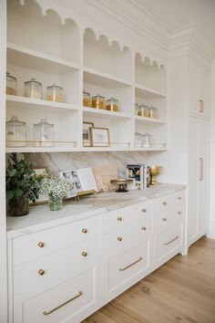 a kitchen with white cabinets and gold pulls on the doors is pictured in this image