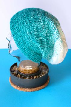 a knitted hat sitting on top of a wooden stand next to a blue background